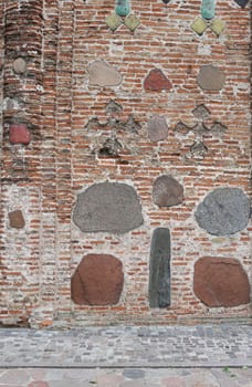 cracked brick wall of rectangular red clay bricks and large stones, cobblestones. The background.