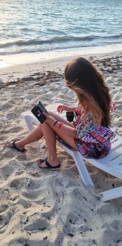 Shot of the woman by the sea shore with the cell phone.