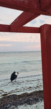 Shot of the woman by the sea shore with the cell phone, at sunrise hour