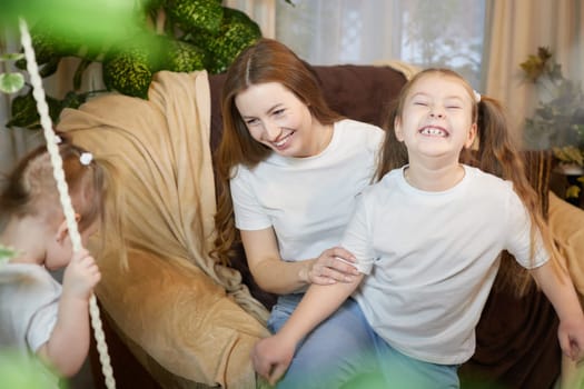 Happy family young mother babysitter relax having fun with cute little children daughters in living room at home