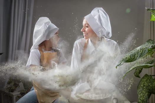 Cute oriental family with mother, daughter cooking in the kitchen on Ramadan, Kurban-Bairam. Funny family at a cook photo shoot with flour. Easter