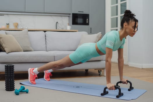 Training to become the best. Beautiful young woman in sports clothing exercising at home.