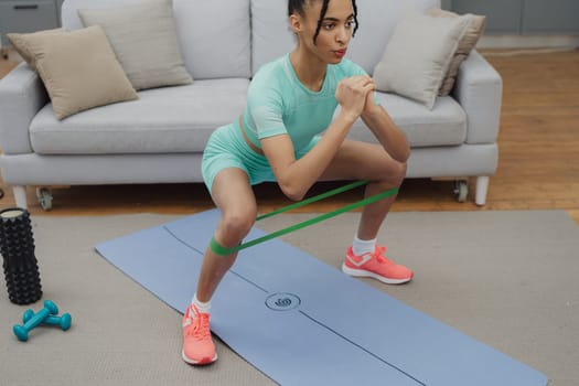 Training to become the best. Beautiful young woman in sports clothing exercising at home.