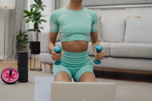 Training to become the best. Beautiful young woman in sports clothing exercising at home.