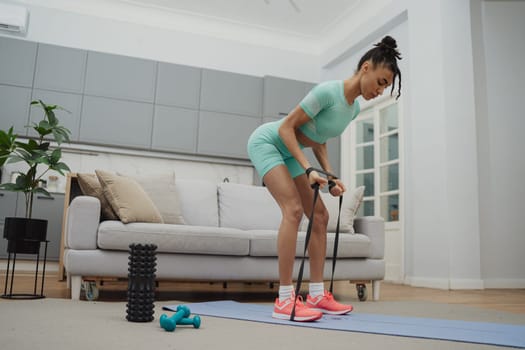 Training to become the best. Beautiful young woman in sports clothing exercising at home.