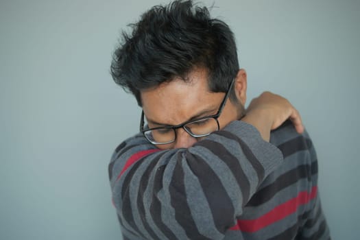 Young ill man covering her nose and mouth with arm