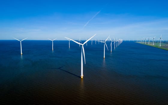 A mesmerizing aerial view of a row of wind turbines swaying gracefully in the ocean breeze off the coast of Flevoland in the Netherlands. windmill turbines energy transition