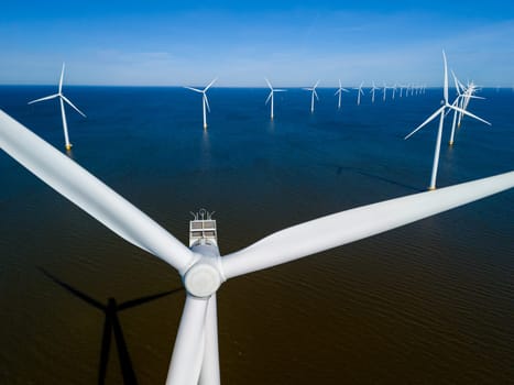 An ocean with wind turbines harnessing the power of the wind to generate clean energy in Flevoland, Netherlands. drone aerial view of windmill turbines green energy in the ocean