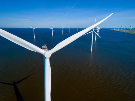A wind farm with towering turbines stands in the middle of a vast body of water, harnessing the power of the wind to generate clean energy in the Netherlands Flevoland during the spring season.