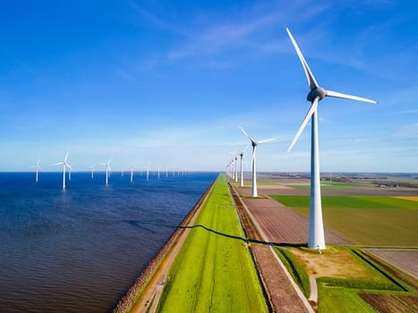 A serene scene in the heart of the Netherlands, where a row of wind turbines gracefully spin next to a peaceful body of water in the vibrant season of Spring. energy transition