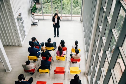 Executive meeting from above, Businesswoman and businessman on chairs discussing teamwork. Diverse colleagues in a conference room, focusing on planning, cooperation, and success.