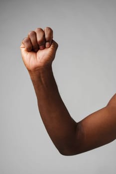 Raised Fist of Determination and Strength Against a Gray Background close up