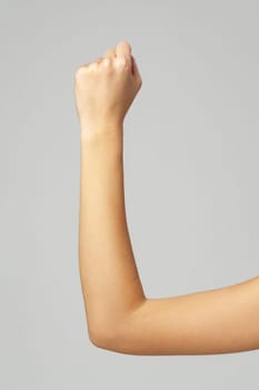 Female hand with clenched fist on gray background close up