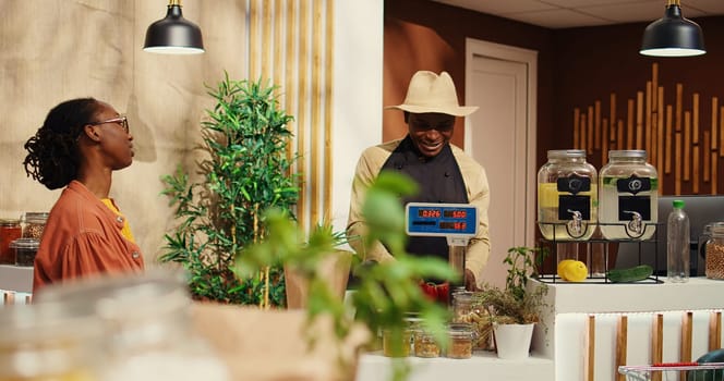 Vegan woman approaching checkout counter to buy produce, choosing organic freshly harvested fruits and vegetables at farmers market. Customer talking to merchant about healthy nutrition. Camera 2.