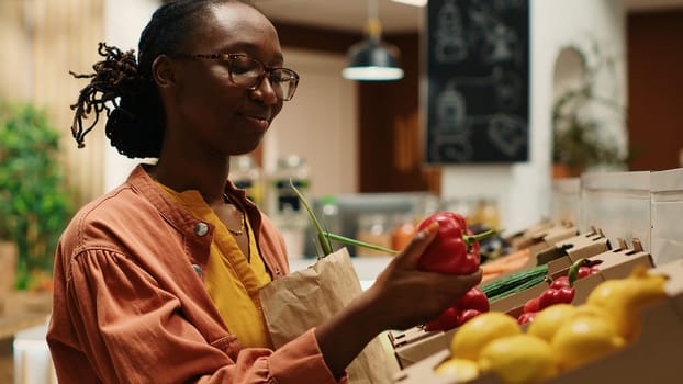 Vegan woman taking locally grown vegetables from crates, going grocery shopping at local farmers market. Regular customer choosing colorful ripe produce, nonpolluting farming business. Camera 1.