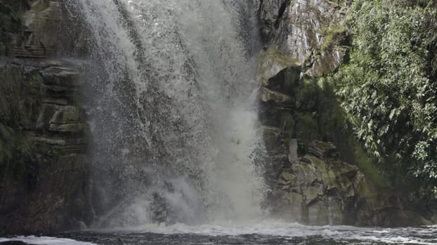 Slow-motion video shows water splashing into a pool amidst nature.