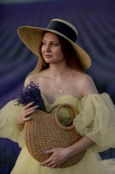 Woman poses in lavender field. Happy woman in yellow dress holds lavender bouquet. Aromatherapy concept, lavender oil, photo session in lavender.