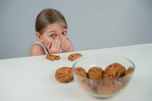 A little girl tries to steal cookies from the table