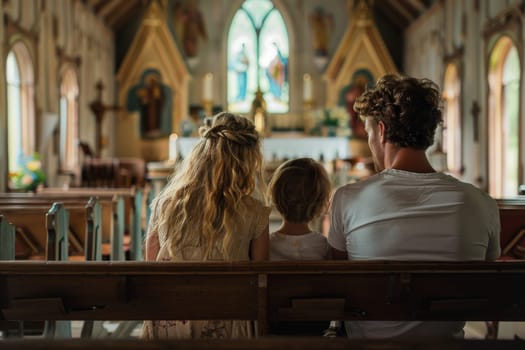 A family of three sits in a church pew. The woman is wearing a floral dress and the man is wearing a white shirt