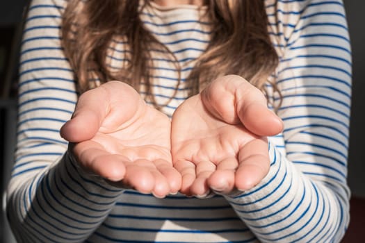 A woman in a striped shirt is extending her hands with a comforting gesture, her fingers slightly wrinkled