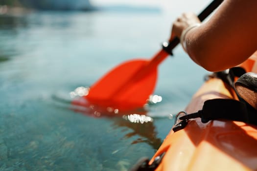 Kayak paddle sea vacation. Person paddles with orange paddle oar on kayak in sea. Leisure active lifestyle recreation activity rest tourism travel.