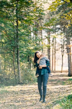 Smiling mother carries a little girl in her arms in a sunny park. High quality photo