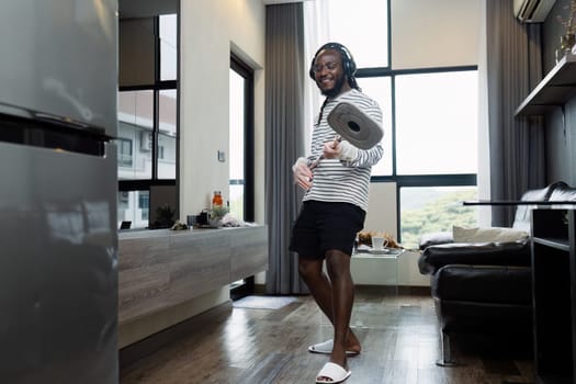 housework concept. African American joyful happy young guy Wipe the floor in living room at home doing housework dancing having fun pretending to play on guitar.