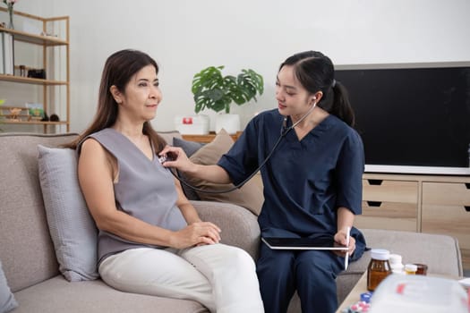 A caregiver and an elderly woman are giving advice and helping with a health check. At the home of an elderly woman.