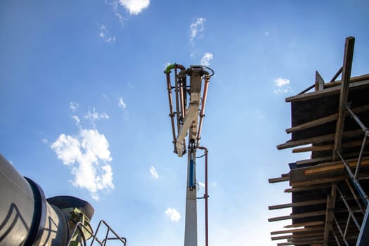 A concrete pump truck deploys a hose to deliver concrete from a concrete mixer to a construction site.