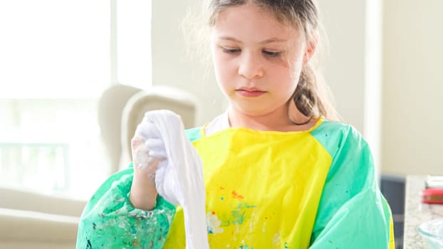 In a modern kitchen, a homeschooled girl is engrossed in creating homemade slime, a fun and educational hands-on project that enhances her creativity and problem-solving skills.