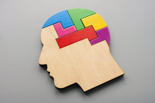 Wooden head made from colored puzzle pieces. Autism, neurodiversity or creativity concept.