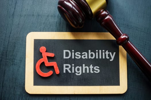 Sign disability rights and gavel on a dark surface.