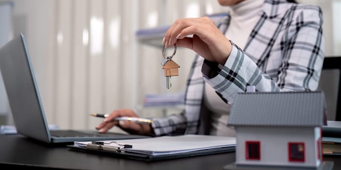 Real estate agent with house model and key.