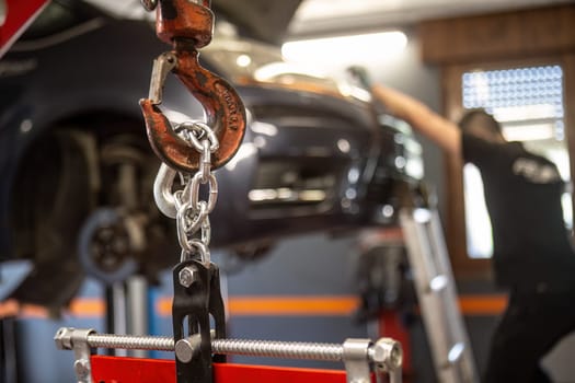 Close-up of an engine being hoisted by a chain in a workshop, emphasizing auto repair service.