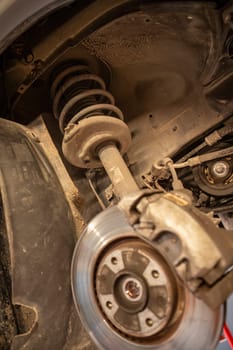 Close-up of a disassembled car suspension shock in workshop, showcasing repair skills.