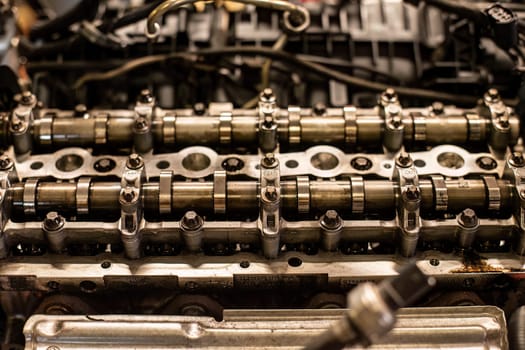 Close-up of a car's disassembled engine showing camshaft detail during workshop repair.