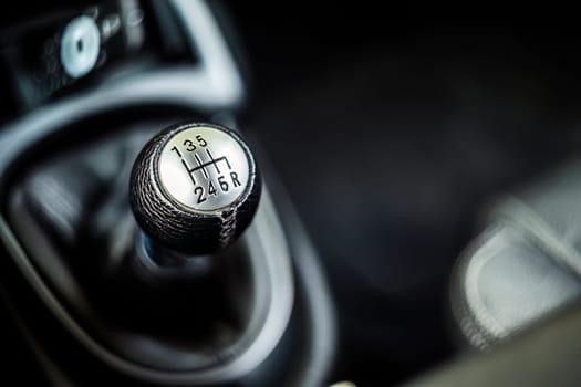 Close-up of a manual gearshift lever in a sports car, epitomizing performance driving.