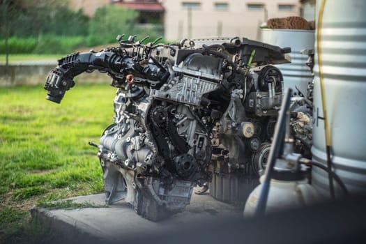 An old, broken engine left outside a workshop, depicting abandonment and repair needs.