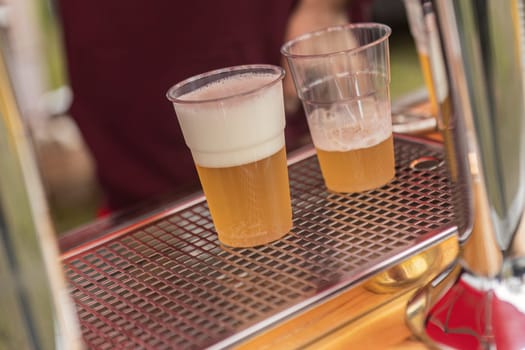 Two glasses of beer are placed on a counter.