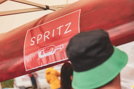 A vibrant "Spritz" sign illuminates above a drink stand, inviting guests to enjoy a refreshing cocktail.