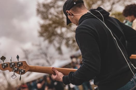 A man standing while holding a guitar in his right hand.