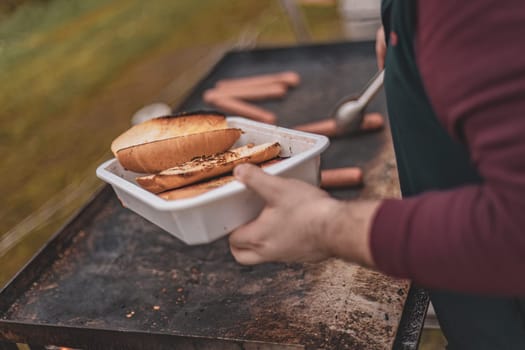 A person is holding a hot dog in a container.