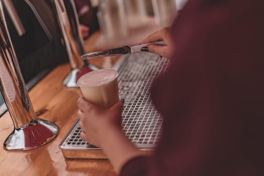 A hand expertly fills a glass with draft beer, capturing the perfect pour and frothy top in action.