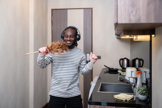 African American man listening to music while cleaning in kitchen.