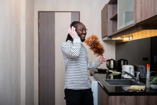 African American man listening to music while cleaning in kitchen.