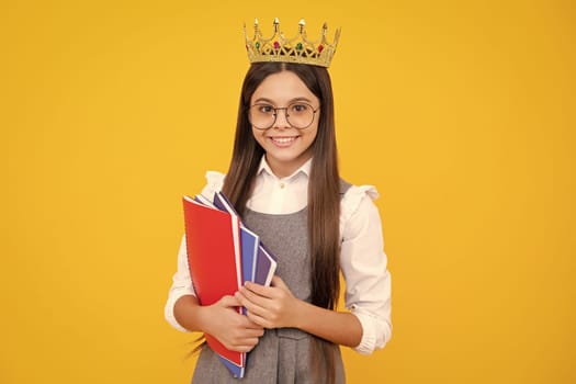 Schoolgirl nerd princess in school uniform and crown celebrating victory on yellow background. School child hold book. Education graduation, victory and success. Happy teenager school girl