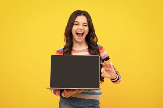 Amazed teenager. Student school girl with laptop on isolated studio background. Screen of laptop computer with copyspace mockup. Excited teen schoolgirl