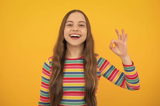 Okay. Portrait of teen girl making ok gesture, isolated background. Young teenager smiling and giving okey sign. Happy cute child showing okay