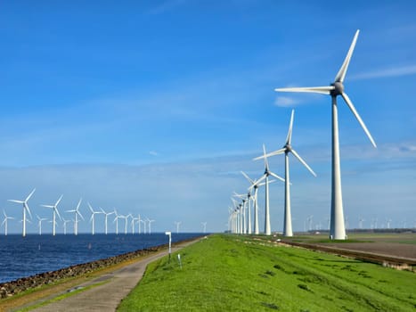 Windmill park in the ocean, view of windmill turbines on a Dutch dike Energy transition, zero emissions, carbon neutral, Earth day concept, windmills isolated at sea in the Netherlands.