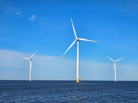 Windmill park in the ocean, view of windmill turbines on a Dutch dike generating green energy electrically, windmills isolated at sea in the Netherlands.